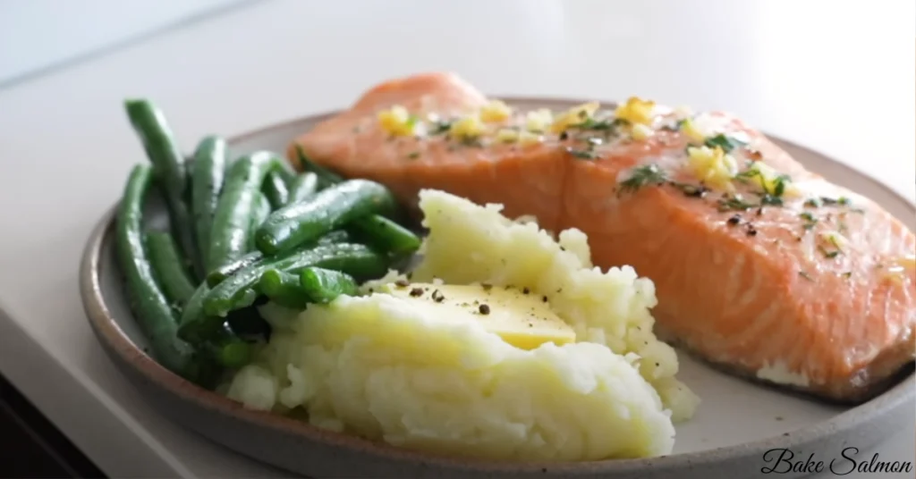 Juicy and tender baked salmon fillet served with roasted vegetables, garnished with parsley on a rustic plate.