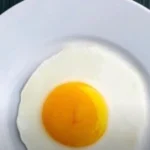 A close-up image of freshly laid eggs in a rustic basket, showcasing a mix of brown and white eggs, with a natural, farm-fresh aesthetic.