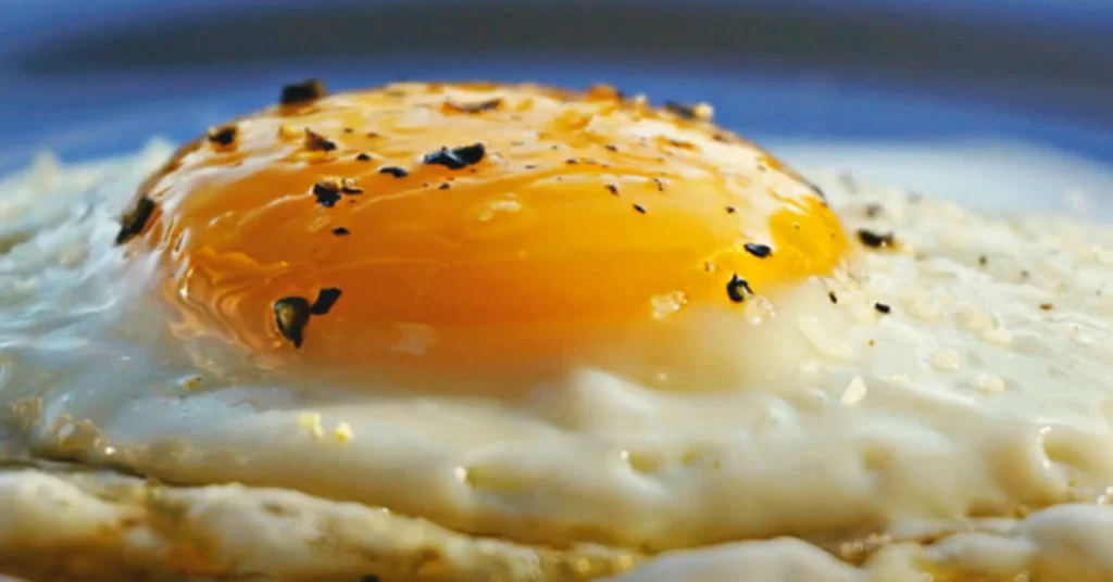 What Questions Can You Ask About Eggs? 3 A wooden kitchen counter with a cracked egg, egg whisk, and ingredients for cooking, emphasizing egg versatility and preparation.
