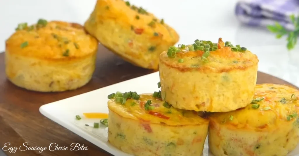 Golden-brown Egg Sausage Cheese Bites on a white plate, served with fresh avocado slices and a side of berries.