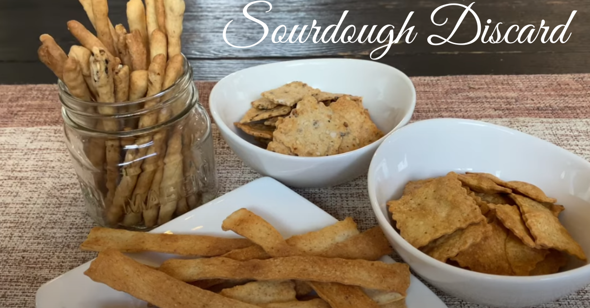 A variety of dishes made from sourdough discard, including pancakes, cookies, and crackers, arranged on a rustic wooden table.