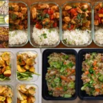 Organized meal prep containers with healthy ingredients like vegetables, grains, and chicken on a kitchen counter.